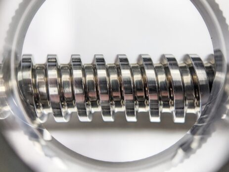Close-Up inspection of a rolled thread bolt with magnifying glass to ensure high quality production
