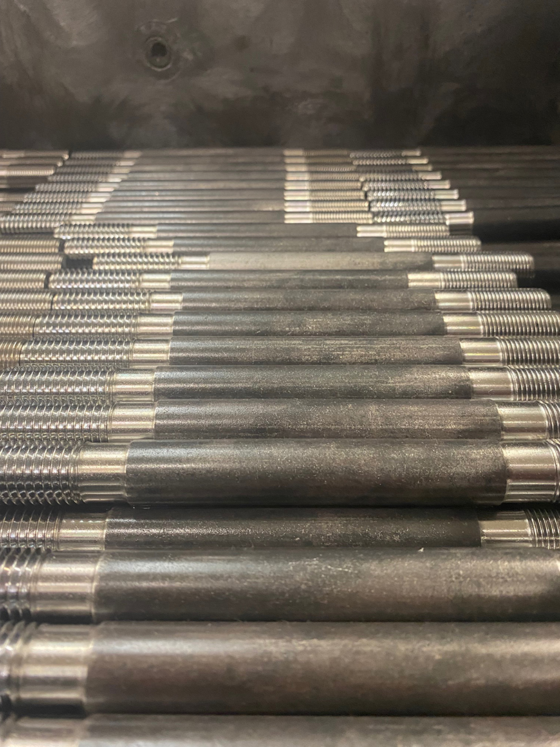 Close-up of a pile of steel tie rods with rolled thread ends