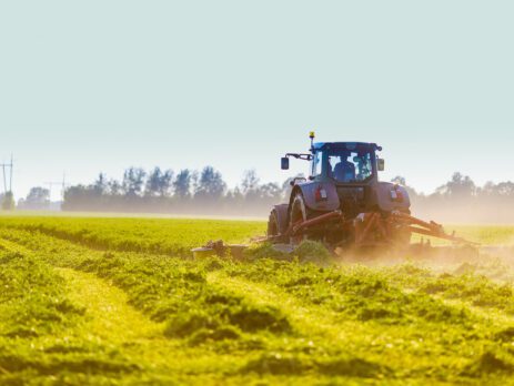 Tractor harvesting hay in field for National Agriculture Month